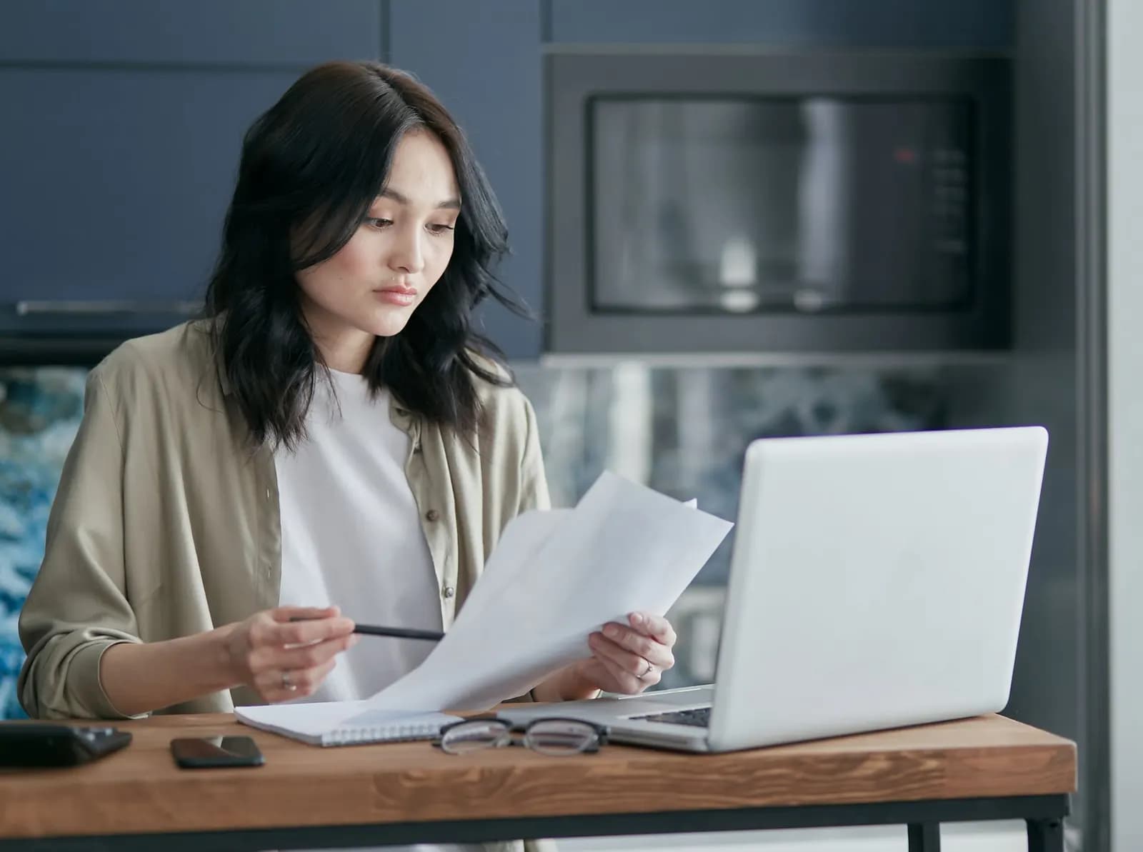 A woman going through papers beside her laptop